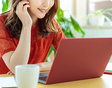 パソコンを見て笑顔になる女性の写真